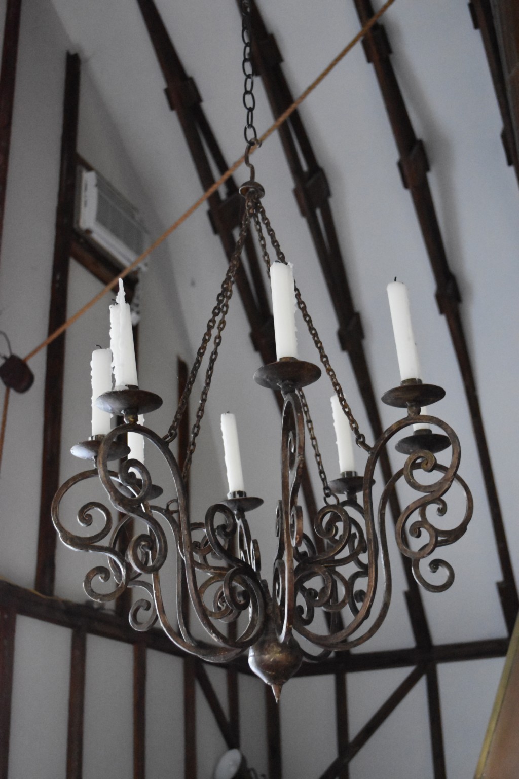 This pretty iron chandelier hangs by a heavy iron chain from the lofty ceiling. No electricity needed, these candles are old school. Love it.